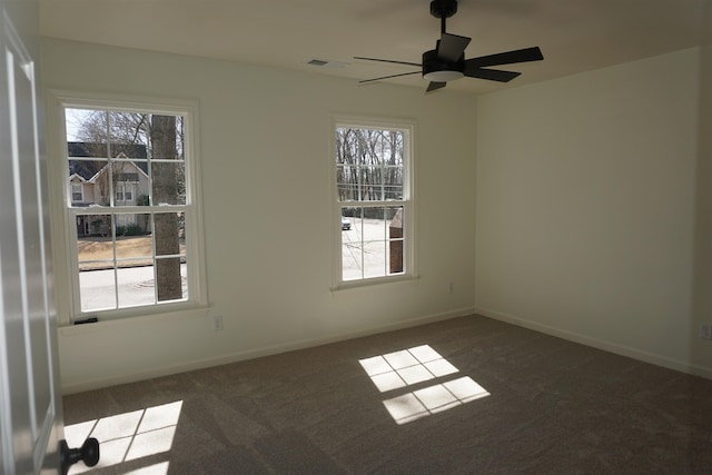 spare room featuring carpet floors, visible vents, ceiling fan, and baseboards