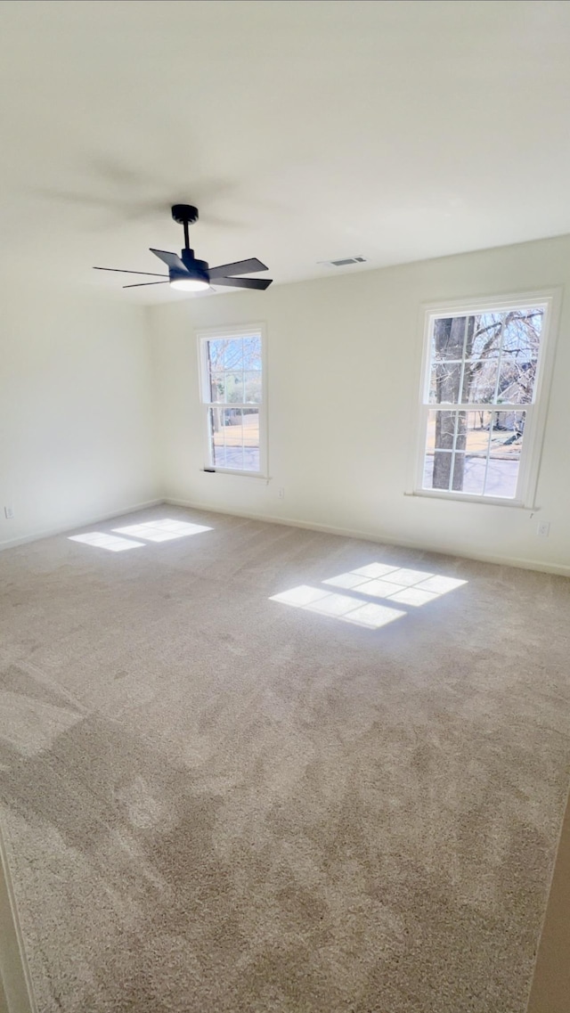 carpeted empty room with ceiling fan and visible vents