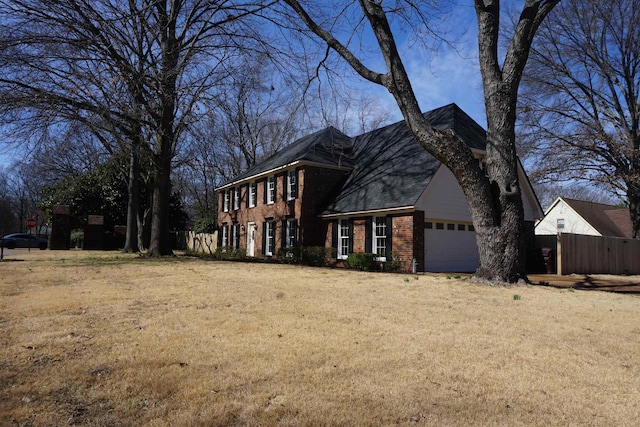 view of home's exterior with a yard, brick siding, an attached garage, and fence