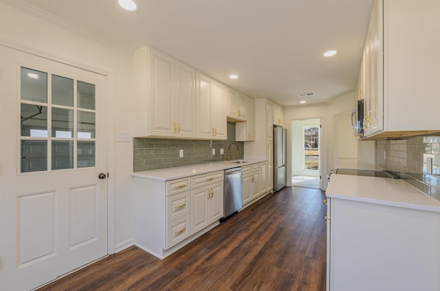 kitchen with appliances with stainless steel finishes, light countertops, a sink, and white cabinetry