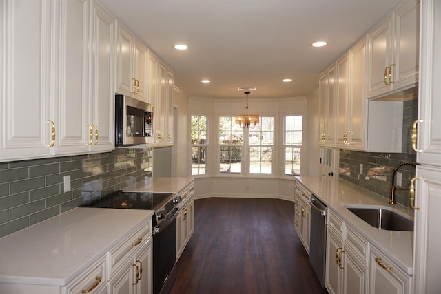 kitchen with dark wood-style floors, backsplash, appliances with stainless steel finishes, white cabinetry, and a sink