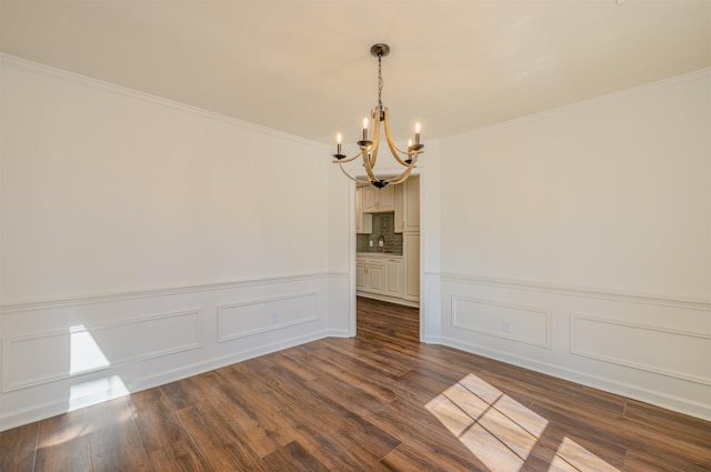 unfurnished room featuring a chandelier, wainscoting, dark wood finished floors, and ornamental molding