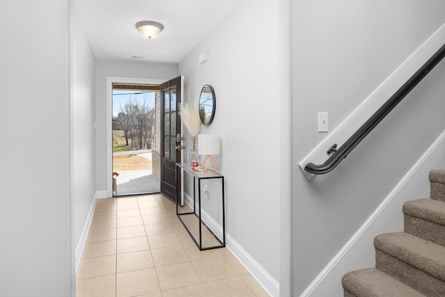 doorway featuring stairway, baseboards, and light tile patterned floors