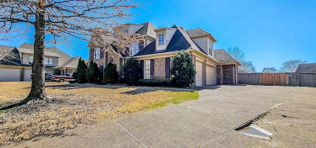 view of front facade with a garage, brick siding, fence, driveway, and a residential view