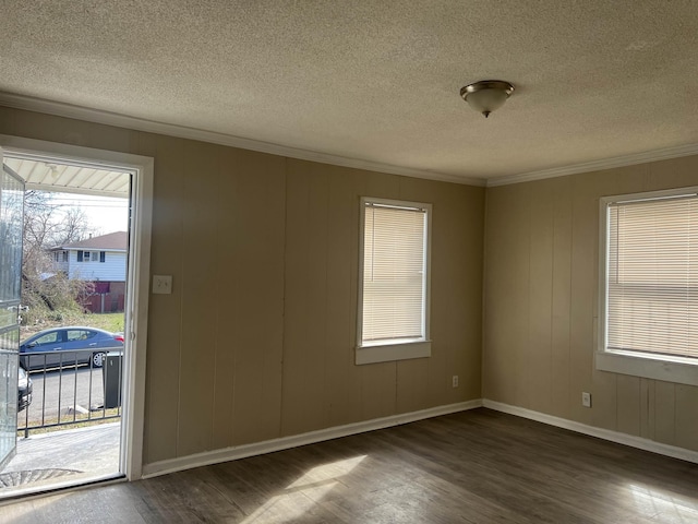 empty room featuring ornamental molding, dark wood-style flooring, a textured ceiling, and baseboards