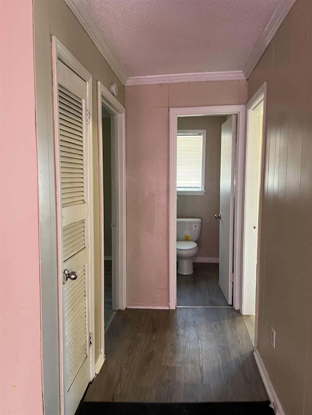 bathroom featuring a textured ceiling, wood finished floors, toilet, and crown molding