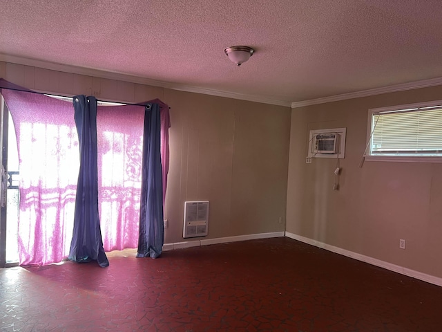 spare room featuring heating unit, baseboards, ornamental molding, and a textured ceiling