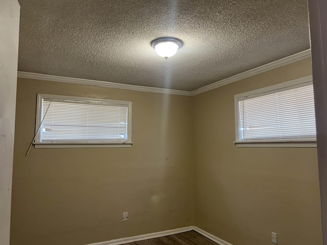 spare room with a textured ceiling, baseboards, wood finished floors, and crown molding