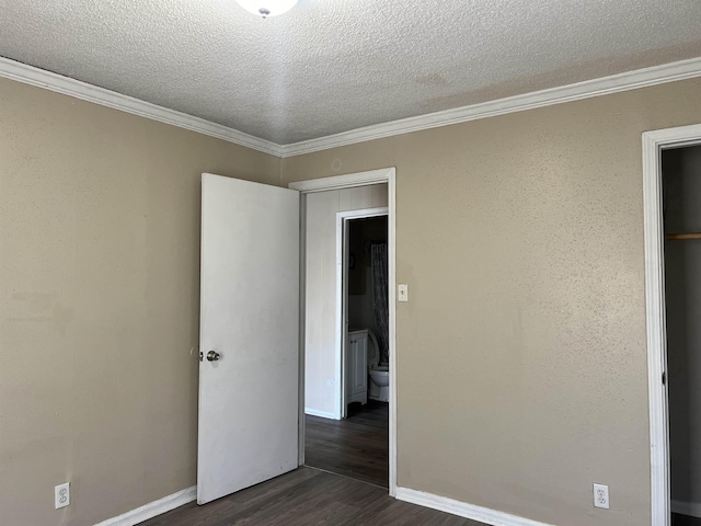 empty room featuring dark wood-style floors, a textured ceiling, and crown molding