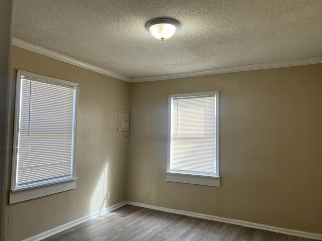 empty room featuring crown molding, a textured ceiling, baseboards, and wood finished floors