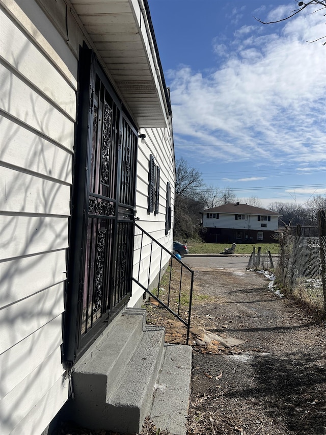 view of side of home featuring entry steps and fence