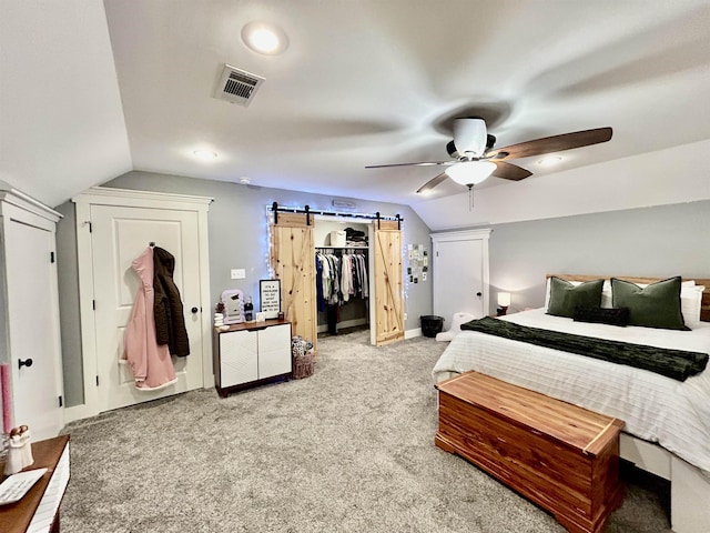 carpeted bedroom featuring a ceiling fan, lofted ceiling, visible vents, and a barn door