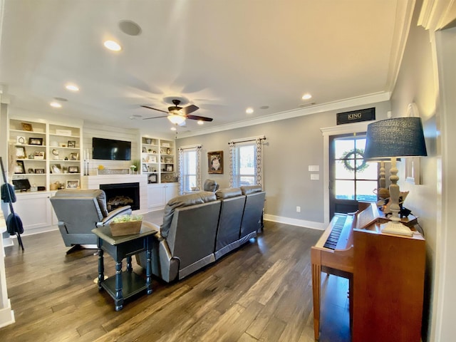 living area with ornamental molding, a fireplace, baseboards, and wood finished floors