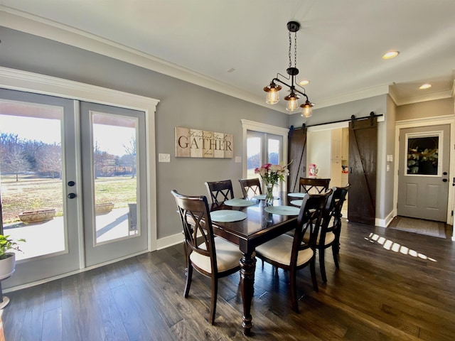 dining area featuring french doors, crown molding, a barn door, dark wood-type flooring, and baseboards