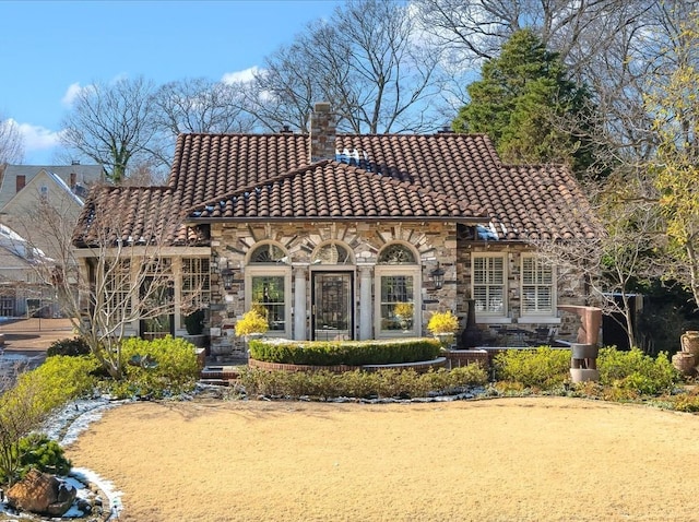 view of front facade with stone siding, a chimney, and a tile roof