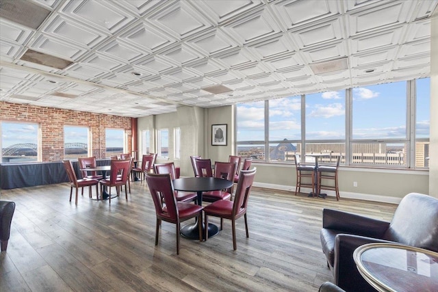 dining room with brick wall, an ornate ceiling, baseboards, and wood finished floors