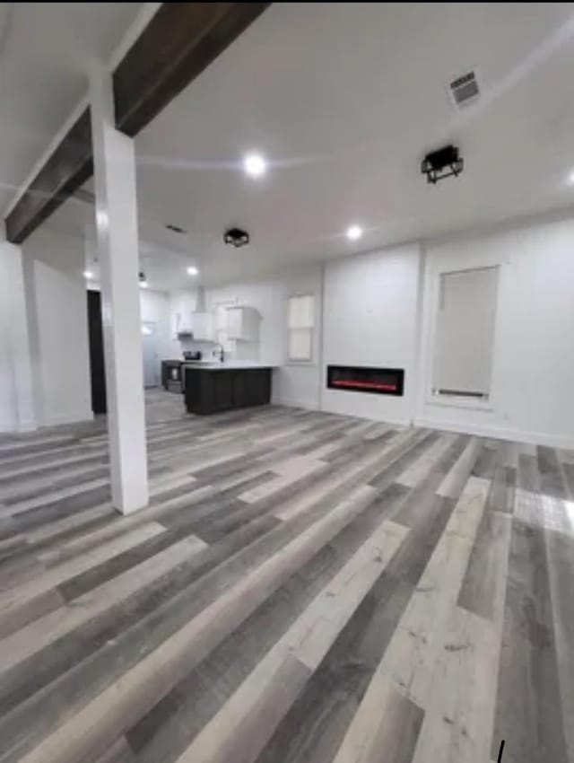 unfurnished living room with a lit fireplace, wood finished floors, visible vents, and recessed lighting