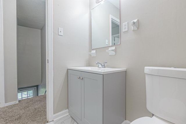 half bath with baseboards, vanity, and toilet