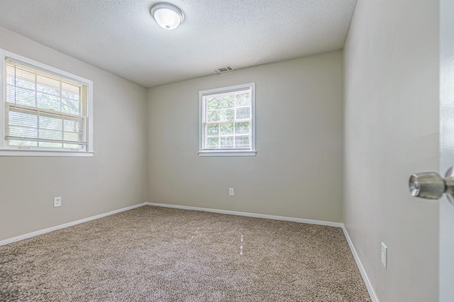 unfurnished room with carpet floors, baseboards, visible vents, and a textured ceiling