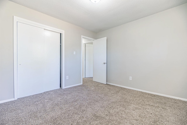 unfurnished bedroom featuring a closet, carpet flooring, a textured ceiling, and baseboards