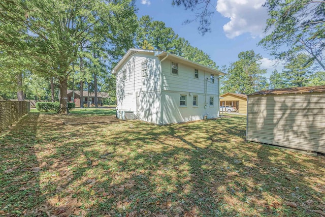 back of house featuring fence, a storage unit, an outdoor structure, and a lawn