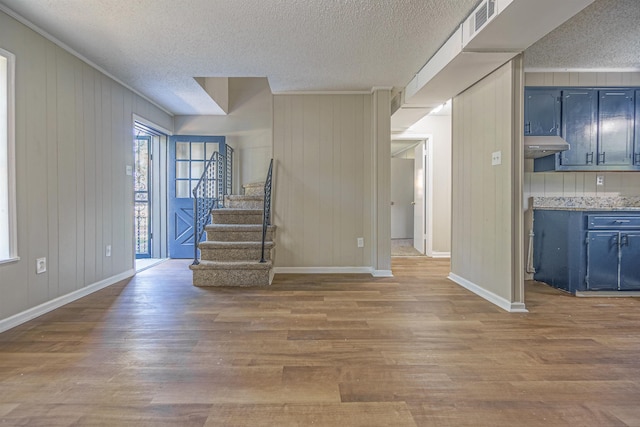 unfurnished living room featuring a textured ceiling, stairway, visible vents, and light wood-style floors