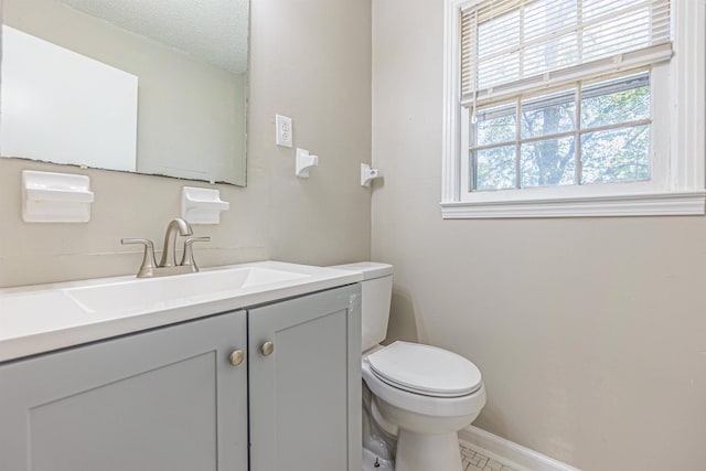 half bathroom featuring toilet, baseboards, a textured ceiling, and vanity