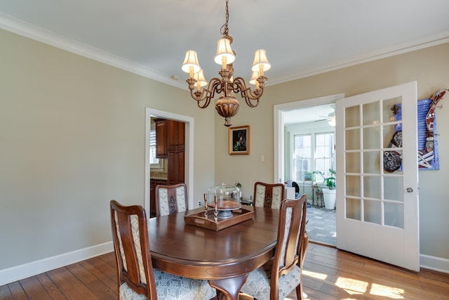 dining area featuring a chandelier, ornamental molding, wood finished floors, and baseboards