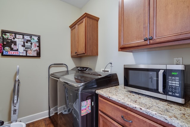 clothes washing area featuring baseboards, dark wood-type flooring, cabinet space, and washer and dryer