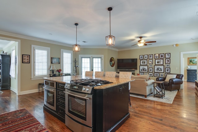 kitchen with a kitchen island, appliances with stainless steel finishes, open floor plan, light stone counters, and hanging light fixtures