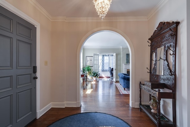 entryway featuring dark wood-type flooring, arched walkways, a chandelier, and crown molding