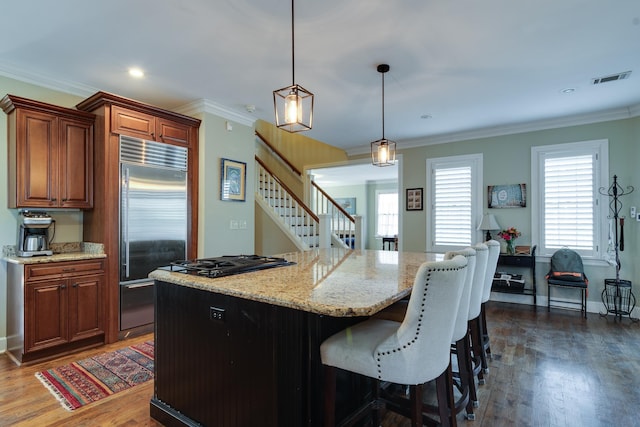 kitchen featuring stainless steel built in fridge, a kitchen island, ornamental molding, and dark wood finished floors