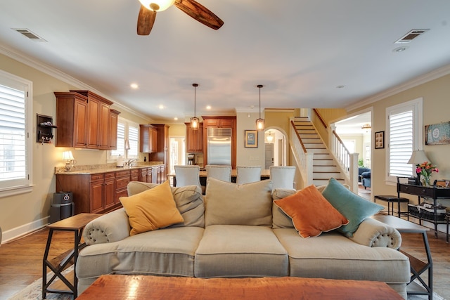 living room featuring a healthy amount of sunlight, wood finished floors, visible vents, and stairs