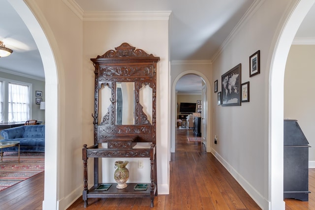 hall with arched walkways, ornamental molding, wood finished floors, and baseboards