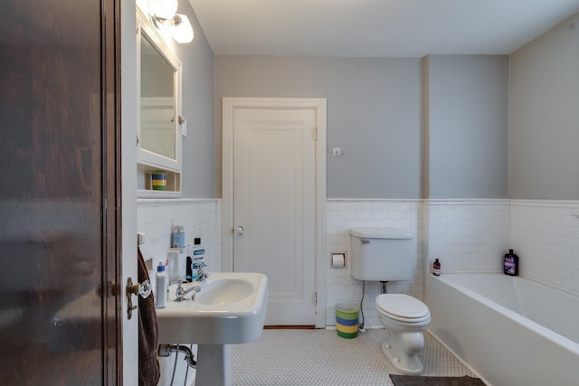 bathroom featuring toilet, tile patterned flooring, tile walls, and a bath