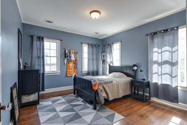 bedroom featuring ornamental molding, dark wood-type flooring, visible vents, and baseboards