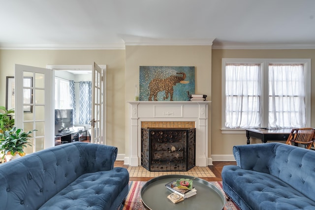 living room featuring light wood-type flooring, baseboards, crown molding, and a tiled fireplace