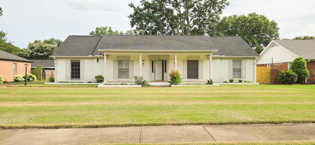 view of front facade with a shingled roof, fence, a front lawn, and brick siding