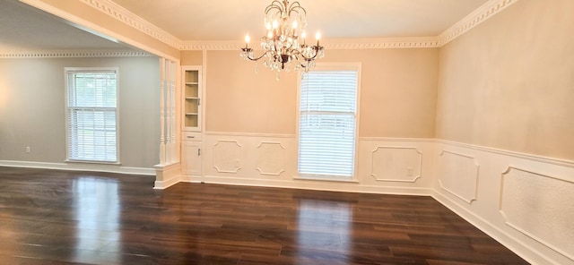 unfurnished dining area featuring a notable chandelier, crown molding, dark wood-type flooring, and wainscoting