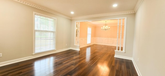 empty room featuring dark wood-style floors, ornamental molding, baseboards, and an inviting chandelier