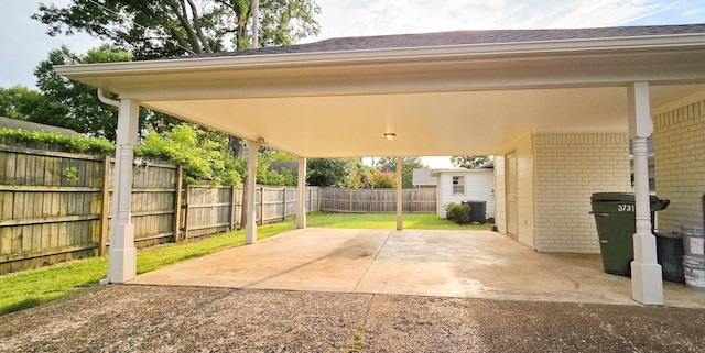 view of patio with a carport, a fenced backyard, and dirt driveway