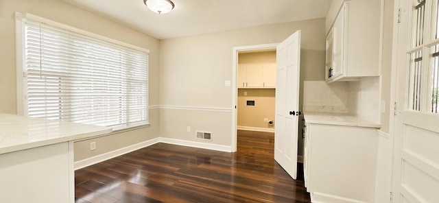 interior space with tasteful backsplash, visible vents, dark wood-type flooring, white cabinetry, and baseboards