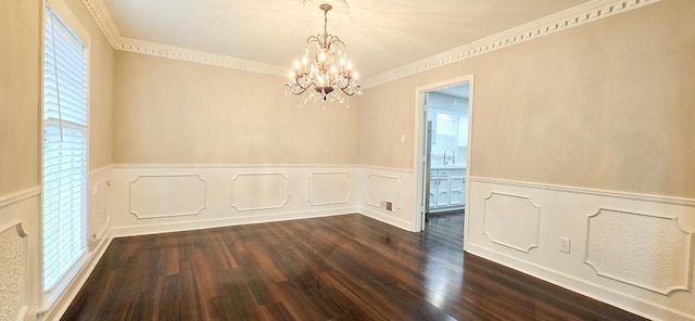 empty room featuring wainscoting, dark wood-type flooring, crown molding, a chandelier, and a sink