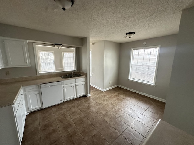 kitchen featuring dishwasher, a sink, a wealth of natural light, and white cabinets