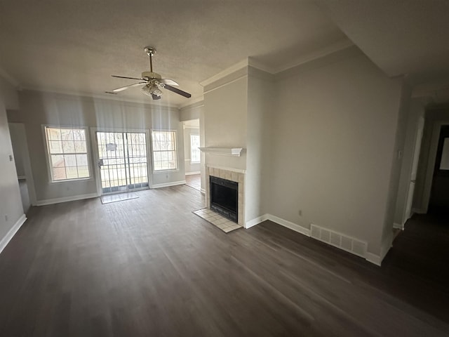 unfurnished living room featuring dark wood-type flooring, a tile fireplace, visible vents, and ornamental molding