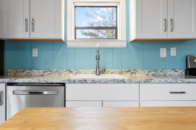 kitchen featuring a sink, light stone countertops, white cabinets, and dishwasher