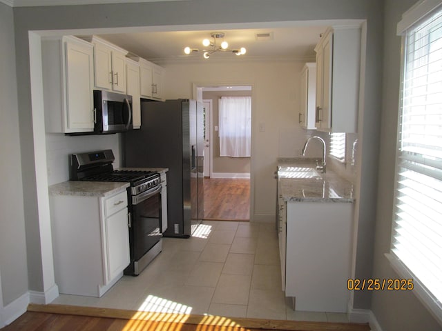 kitchen with tasteful backsplash, white cabinets, appliances with stainless steel finishes, light stone counters, and a sink