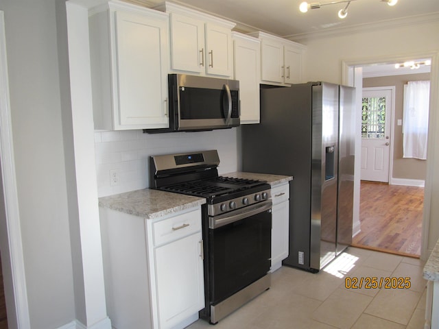 kitchen featuring stainless steel appliances, white cabinetry, ornamental molding, backsplash, and light stone countertops