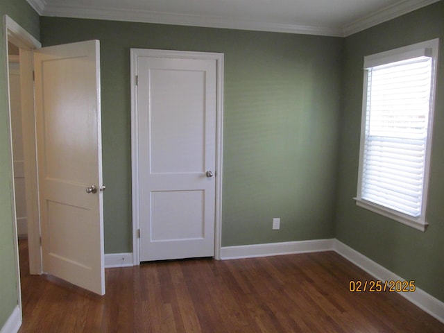 unfurnished bedroom featuring dark wood-type flooring, crown molding, and baseboards