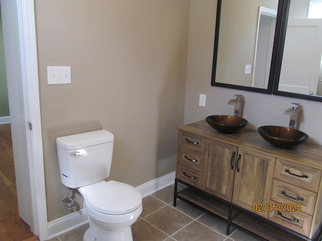 bathroom with double vanity, a sink, toilet, and tile patterned floors